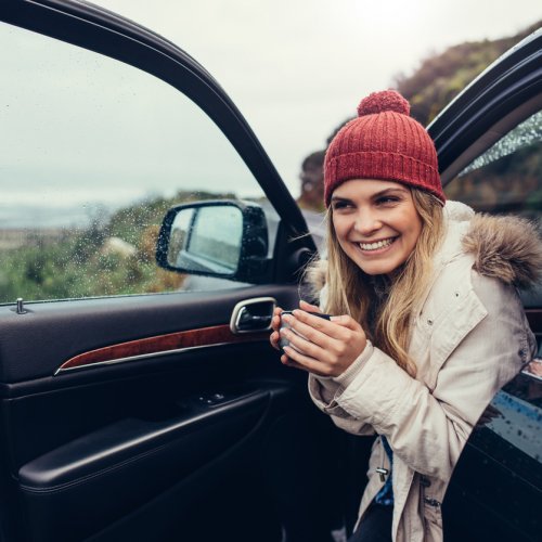 Beautiful smiling woman in her car drinking coffee Easirent car hire liverpool